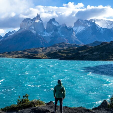 a man standing on top of a mountain next to a lake